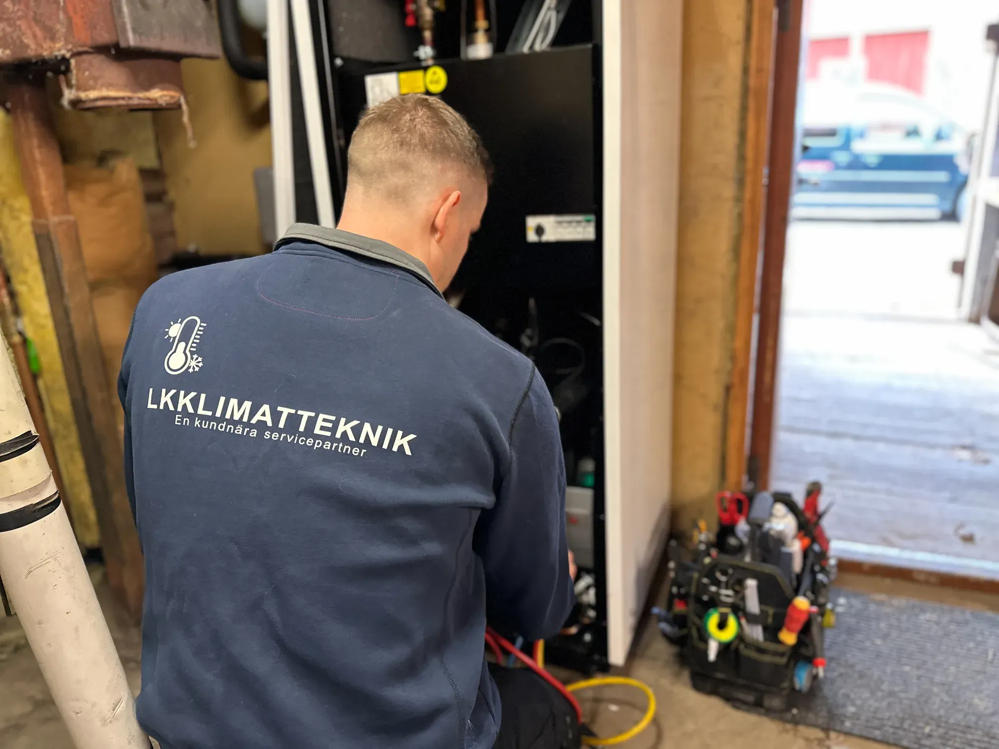 Installatör i LK Klimatteknik-jacka arbetar med en anläggning inomhus